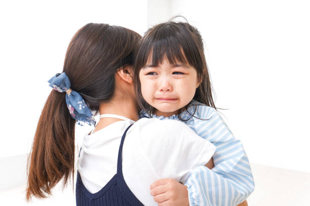 泣く子どもを抱っこするママ